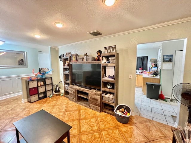 living area with ornamental molding, light tile patterned flooring, visible vents, and a textured ceiling