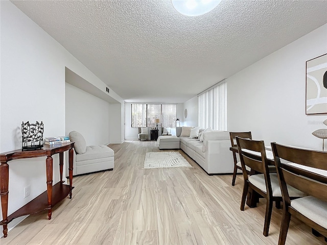 living area with a textured ceiling, light wood finished floors, and visible vents