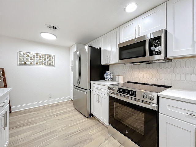 kitchen featuring appliances with stainless steel finishes, white cabinetry, and decorative backsplash