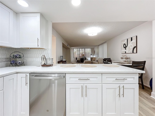 kitchen featuring decorative backsplash, white cabinets, dishwasher, a peninsula, and light wood-style floors