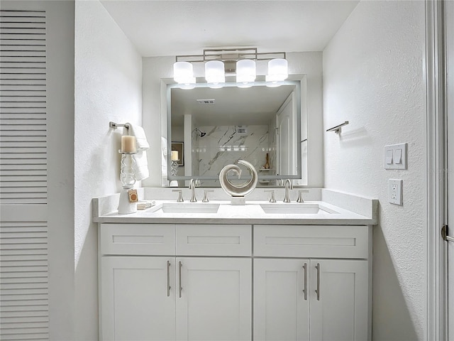 bathroom with visible vents, a tile shower, a sink, and double vanity