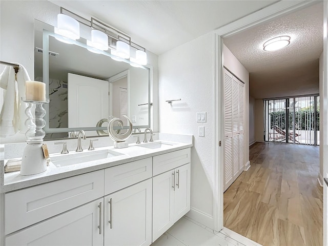 bathroom featuring a sink, a textured ceiling, baseboards, and double vanity