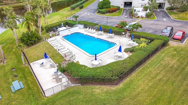 pool with a water view, fence, and a patio