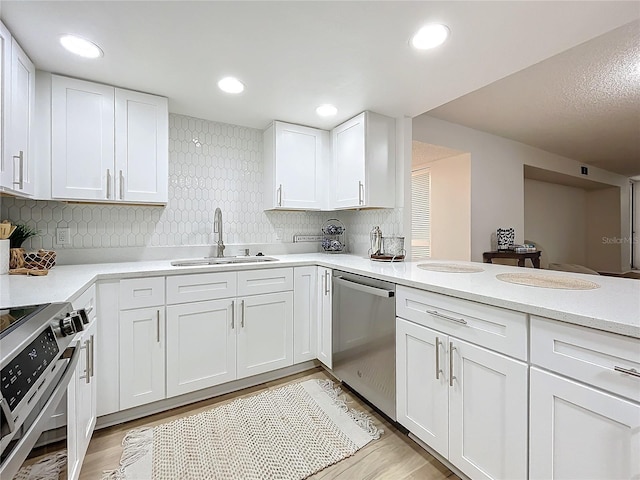 kitchen with light countertops, appliances with stainless steel finishes, light wood-style floors, white cabinets, and a sink