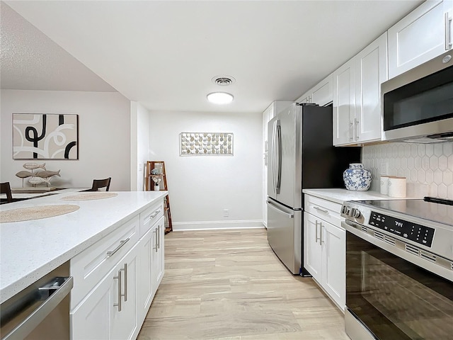 kitchen featuring appliances with stainless steel finishes, white cabinets, visible vents, and tasteful backsplash