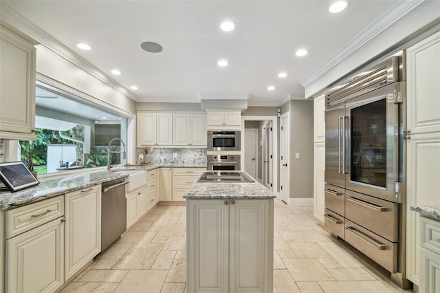 kitchen featuring sink, backsplash, light stone counters, a kitchen island, and stainless steel appliances