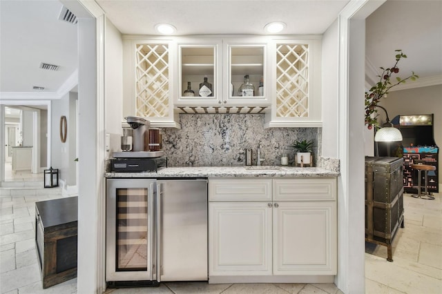 bar featuring wine cooler, fridge, white cabinets, tasteful backsplash, and light stone counters