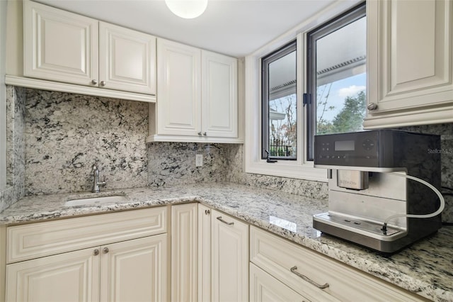 kitchen with sink, light stone counters, and tasteful backsplash