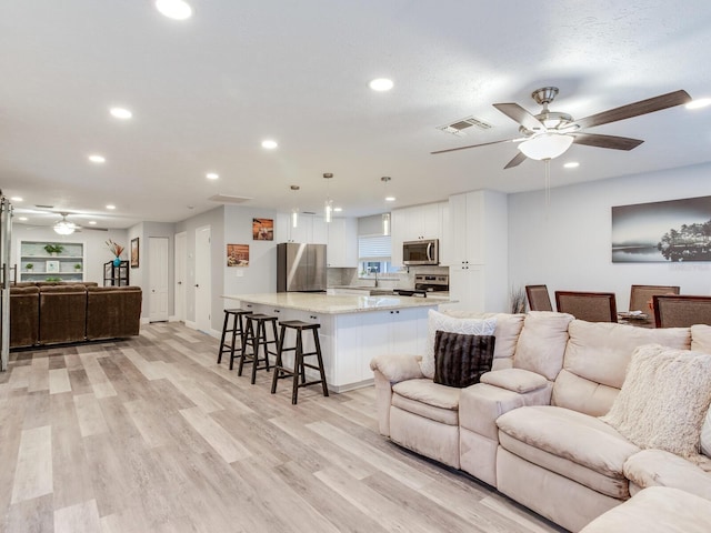 living room with ceiling fan and light hardwood / wood-style flooring