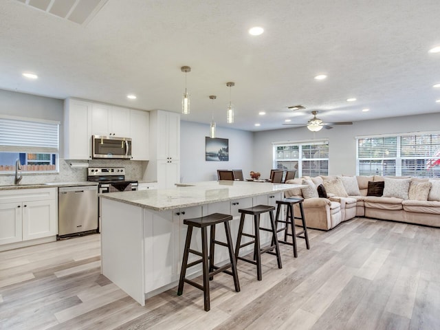 kitchen with appliances with stainless steel finishes, decorative light fixtures, a center island, and white cabinets