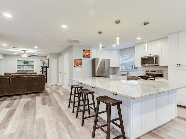 kitchen with appliances with stainless steel finishes, sink, white cabinets, and a spacious island