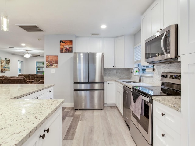 kitchen with sink, light stone counters, appliances with stainless steel finishes, decorative backsplash, and white cabinets