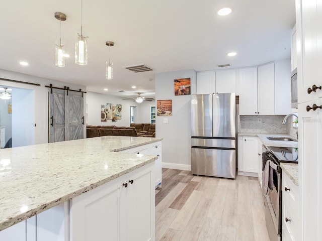 kitchen with appliances with stainless steel finishes, sink, white cabinets, and light stone counters