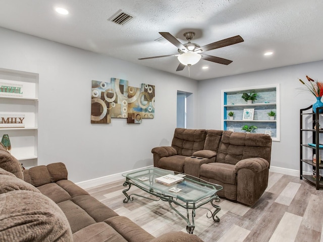 living room featuring ceiling fan, a textured ceiling, and light wood-type flooring