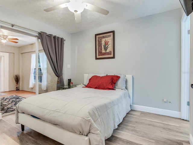 bedroom featuring ceiling fan, light hardwood / wood-style floors, and a textured ceiling