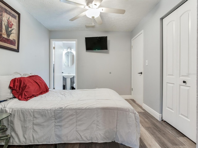 bedroom featuring connected bathroom, wood-type flooring, a textured ceiling, a closet, and ceiling fan