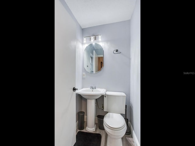 bathroom with wood-type flooring, toilet, sink, and a textured ceiling