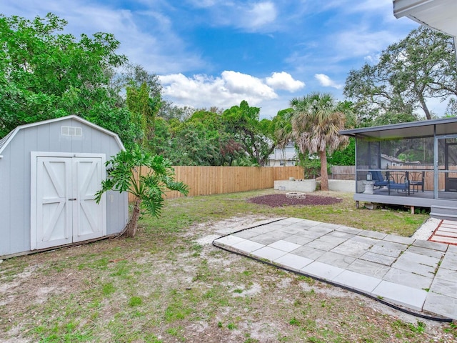 view of yard featuring a storage shed, a wooden deck, a sunroom, and a patio