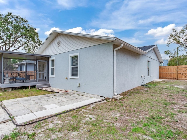 rear view of property with a wooden deck, a sunroom, and a patio