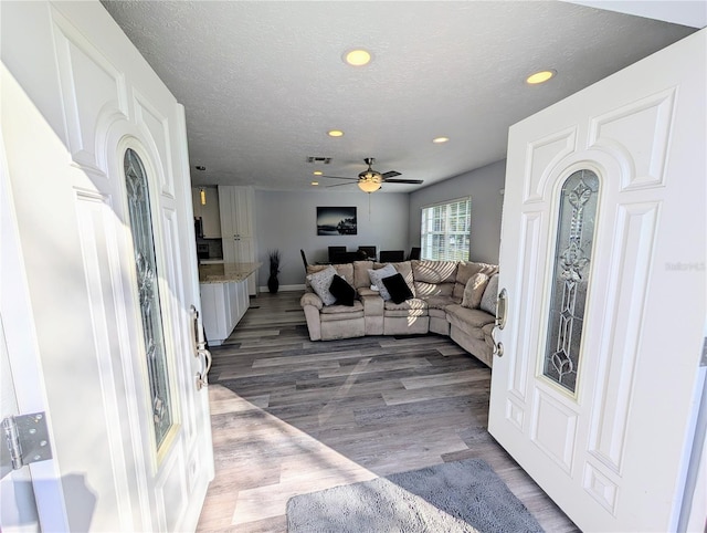 living room with hardwood / wood-style flooring, ceiling fan, and a textured ceiling