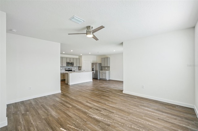 unfurnished living room with ceiling fan, a textured ceiling, and wood-type flooring