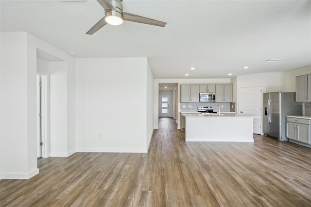 unfurnished living room with wood-type flooring, sink, and ceiling fan