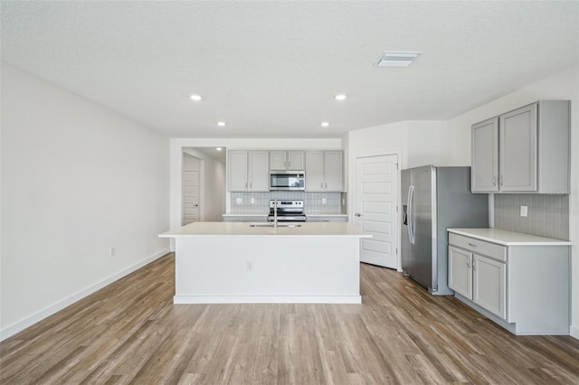 31814 Oyster Trellis Ln, Wesley Chapel, FL 33545 - kitchen featuring appliances with stainless steel finishes, gray cabinets, backsplash, light wood finished floors, and recessed lighting