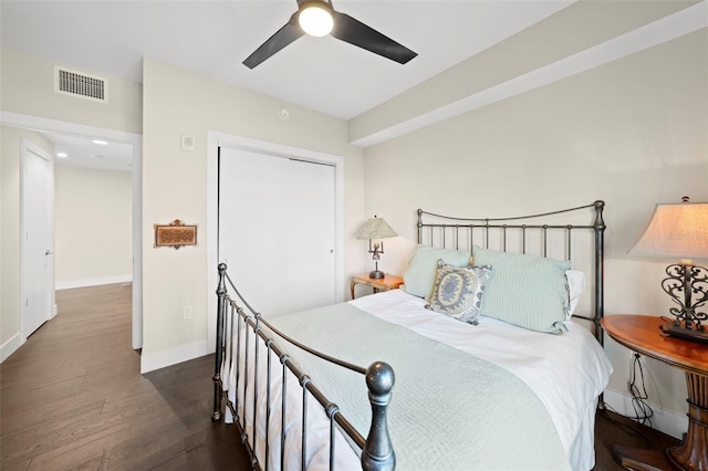 bedroom with dark wood-type flooring, ceiling fan, and a closet