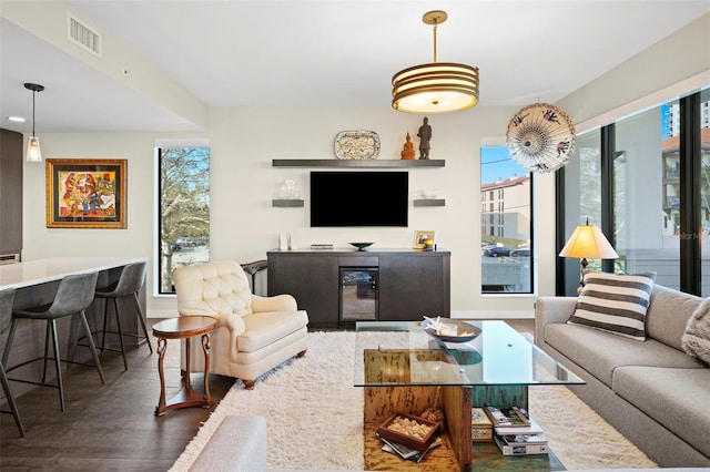 living room with bar, dark wood-type flooring, and beverage cooler