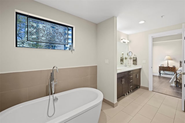 bathroom featuring a tub, tile walls, tile patterned floors, and vanity