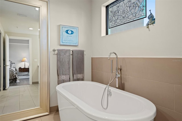 bathroom with a bathing tub, tile patterned flooring, and tile walls