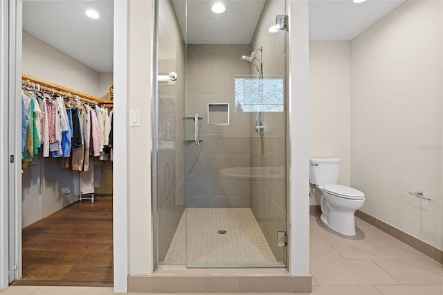 bathroom featuring toilet, tile patterned floors, and a shower with shower door