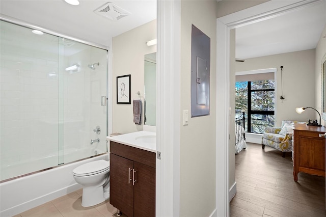 full bathroom with wood-type flooring, vanity, bath / shower combo with glass door, toilet, and electric panel