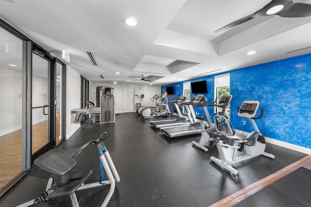 workout area featuring ceiling fan and a tray ceiling