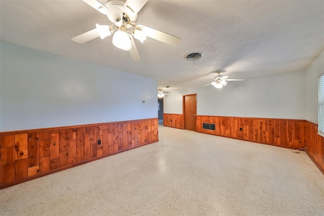 unfurnished room with ceiling fan and wood walls