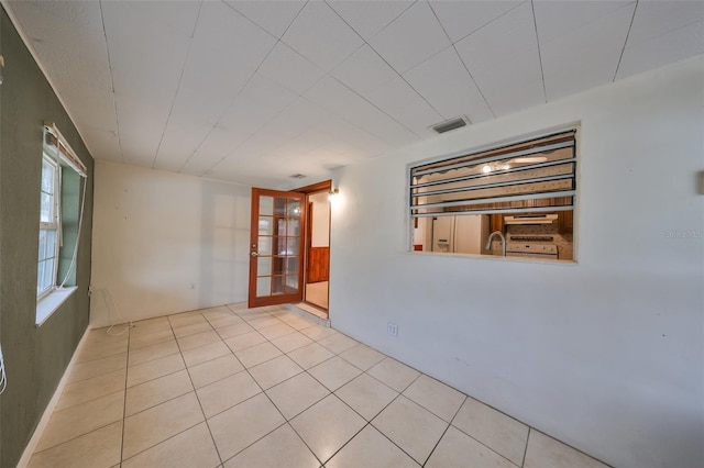 unfurnished room featuring sink, light tile patterned floors, and french doors