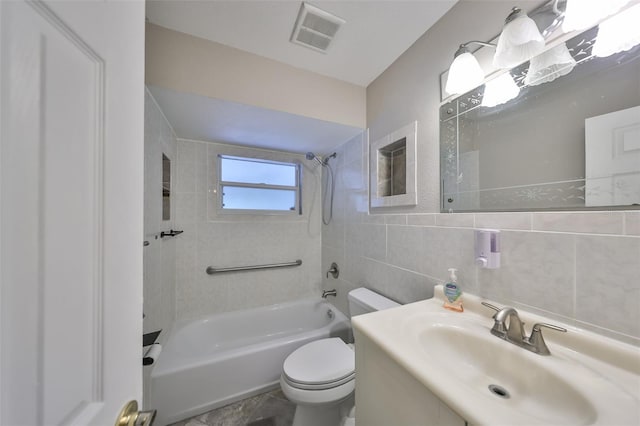 full bathroom with toilet, tile walls, vanity, and tiled shower / bath combo