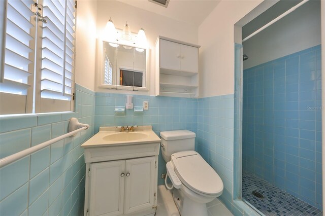 bathroom with toilet, vanity, tile walls, and a tile shower