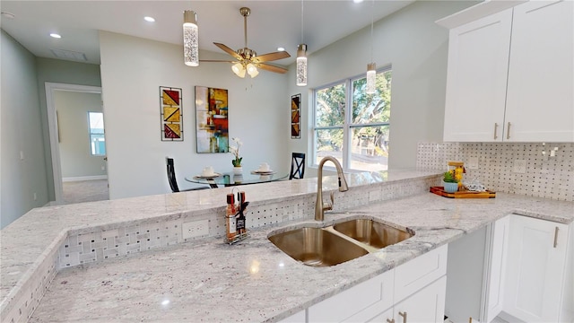 kitchen featuring ceiling fan, white cabinets, sink, and light stone counters