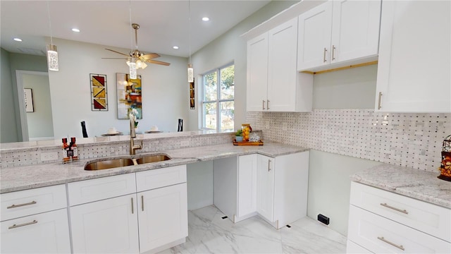 kitchen with light stone countertops, white cabinetry, tasteful backsplash, sink, and ceiling fan