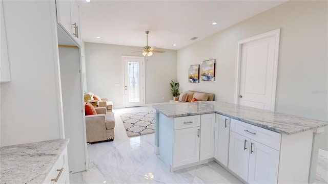 kitchen with ceiling fan, white cabinets, and light stone countertops