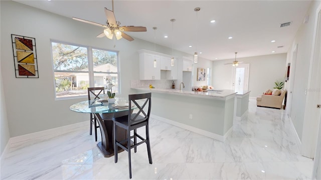 kitchen with decorative light fixtures, tasteful backsplash, ceiling fan, a kitchen bar, and white cabinetry