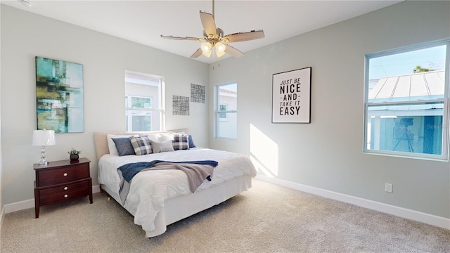 bedroom with ceiling fan, light colored carpet, and multiple windows