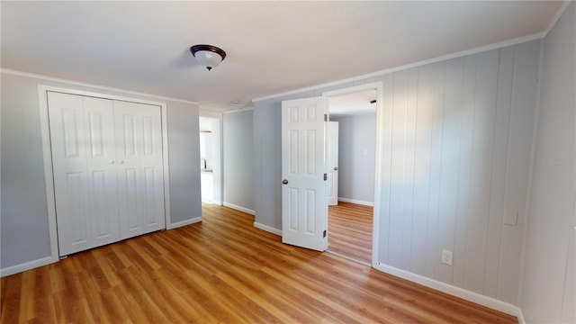 unfurnished bedroom featuring a closet, crown molding, and light hardwood / wood-style floors