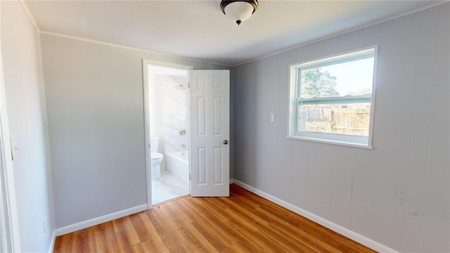 unfurnished bedroom featuring light wood-type flooring, connected bathroom, and ornamental molding