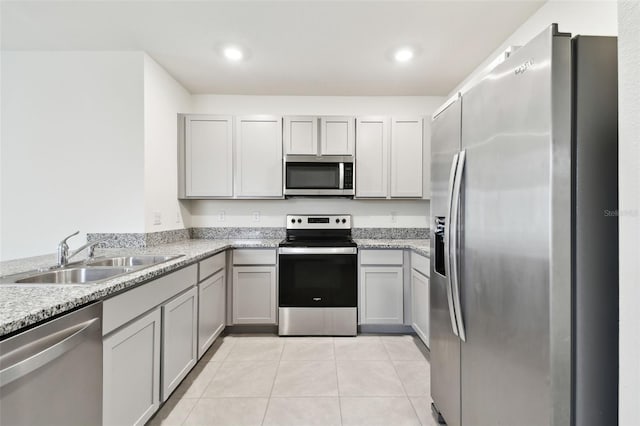 kitchen featuring light tile patterned flooring, stainless steel appliances, gray cabinetry, and sink