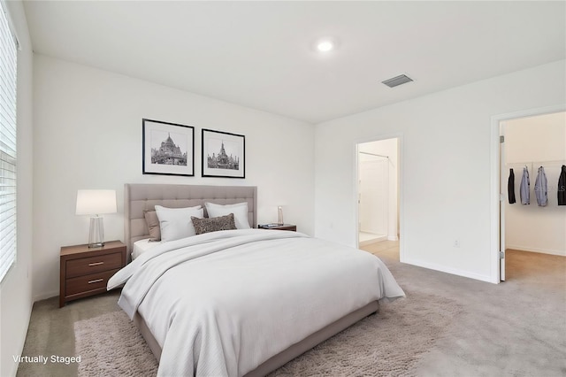 carpeted bedroom featuring a spacious closet, ensuite bathroom, and a closet