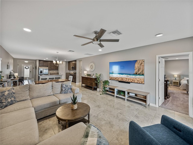 living room with light tile patterned flooring and ceiling fan with notable chandelier