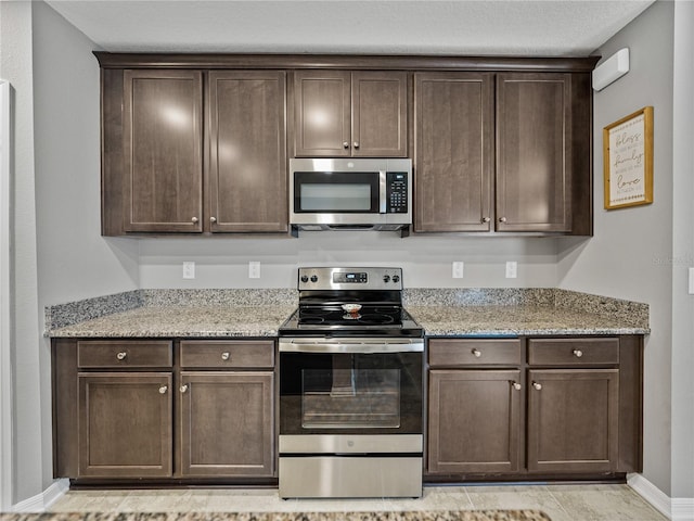 kitchen featuring appliances with stainless steel finishes, light stone counters, and dark brown cabinetry