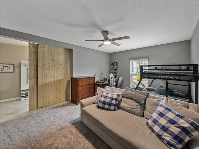 bedroom with ceiling fan, light colored carpet, and a textured ceiling